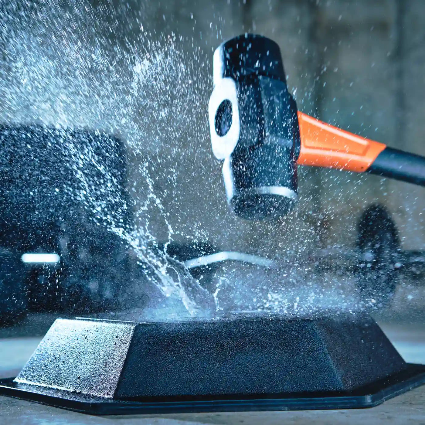 Sledgehammer striking the HAXE Slam Pad with water splashing on impact