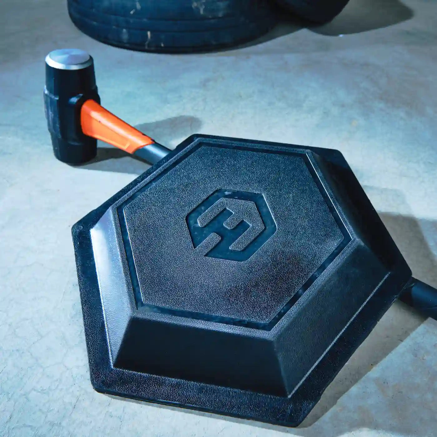 HAXE Slam Pad leaning against a sledgehammer in a garage gym setting